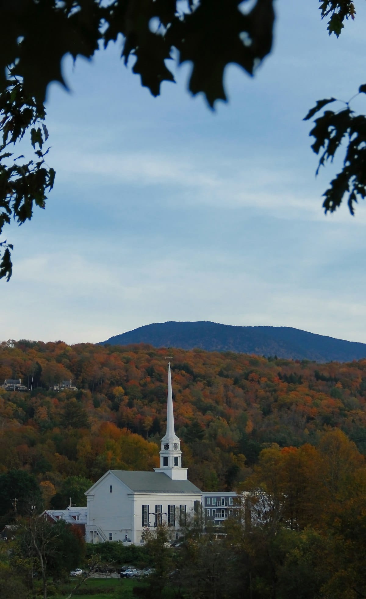 White church steeple rising above autumn foliage in a quaint New England village — a scene typical of small Vermont towns like Jamaica